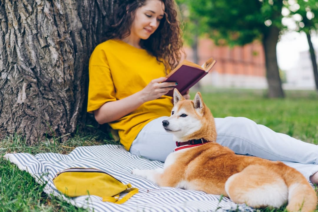 service dog public access. A woman reading a book next to a dog