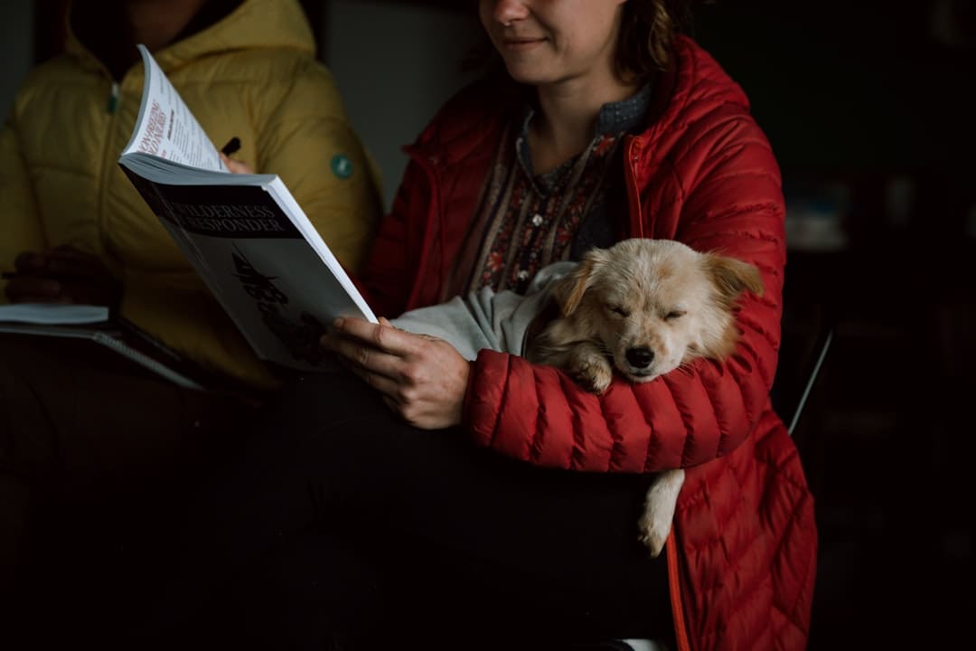 support animal species. A woman reading a book with a dog in her lap