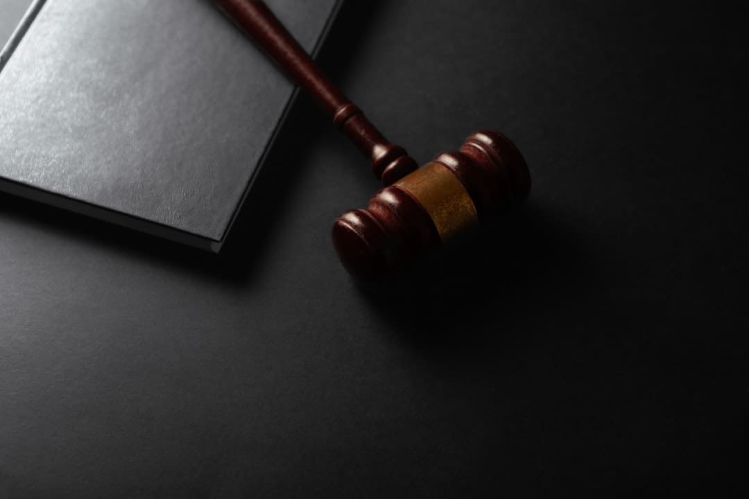 support animal fraud laws — Wooden gavel resting on a dark surface next to book