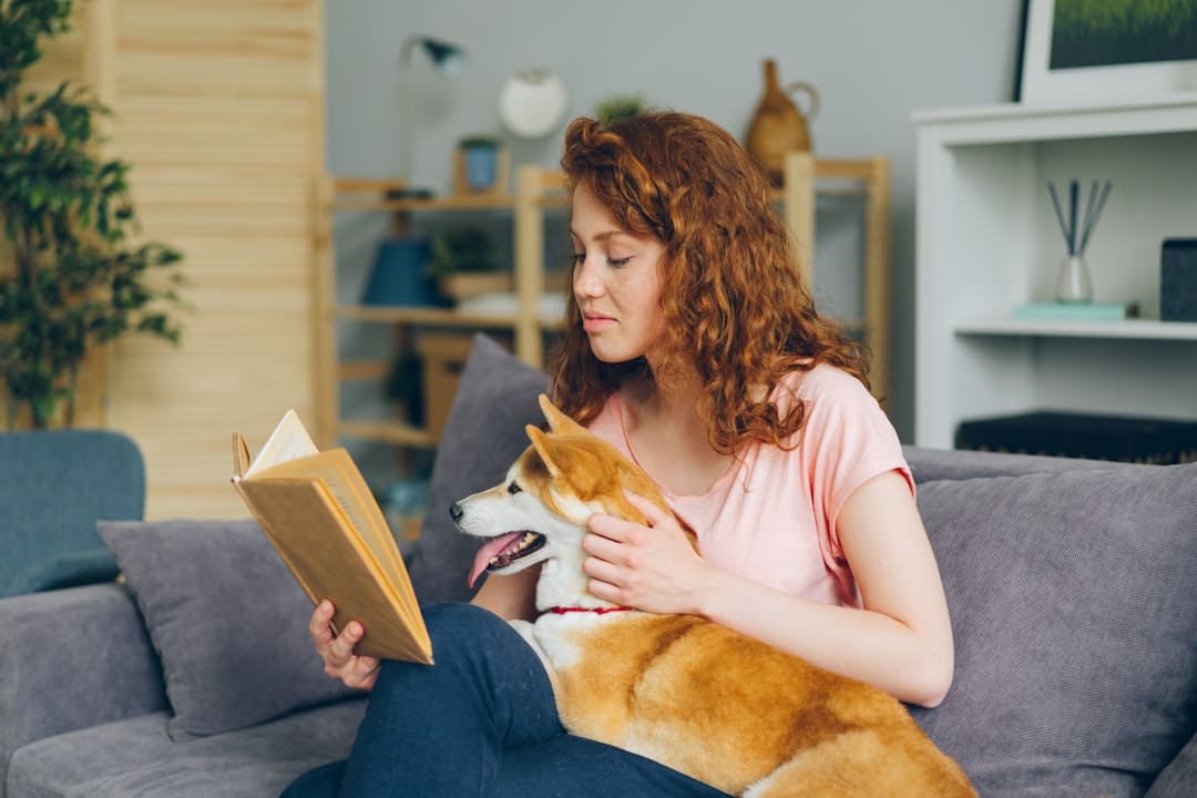 breed restrictions support animals — a woman sitting on a couch reading a book with her dog