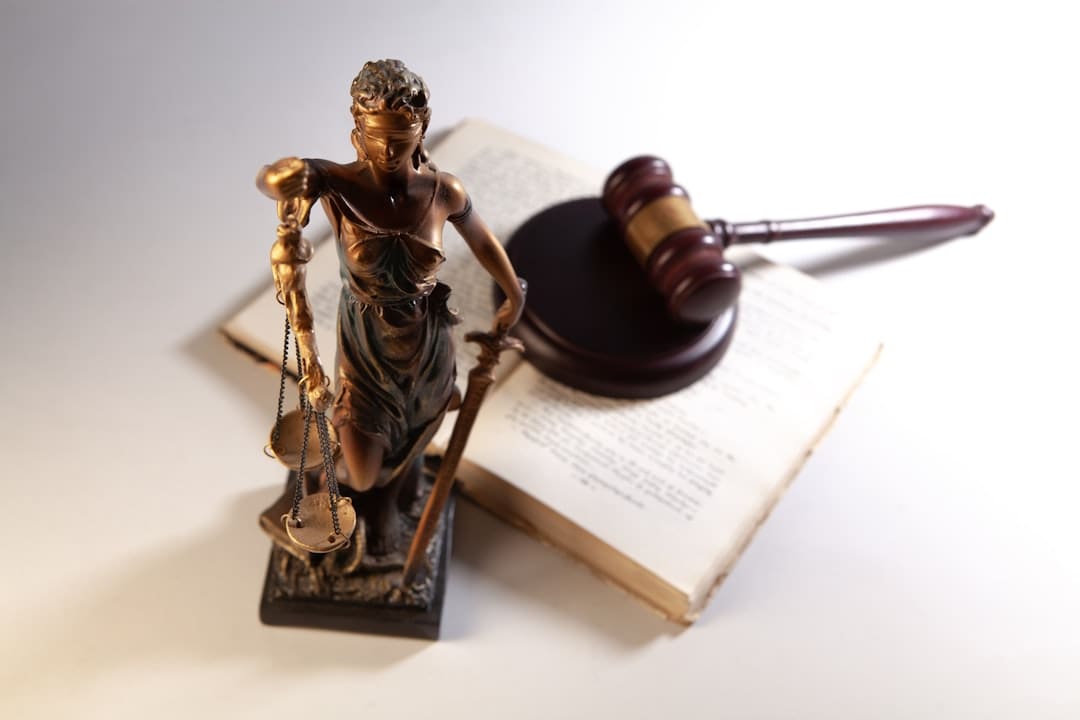 support animal fraud — Statue of justice, gavel, and open book on table.