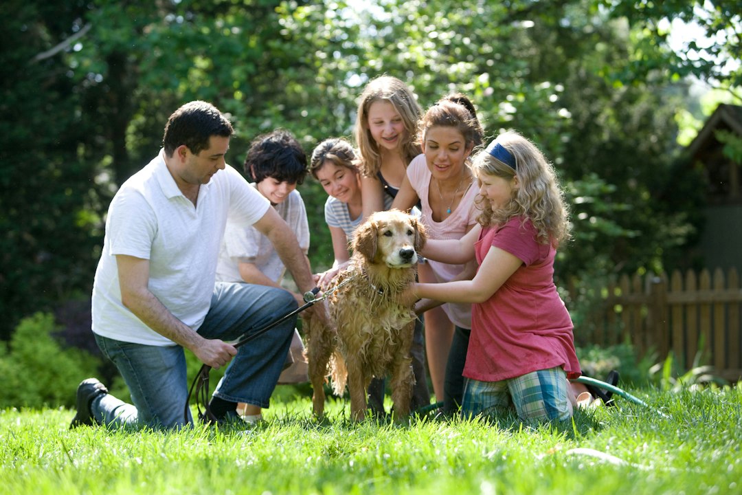 HUD guidance withdrawal — A family washing a golden retriever in a sunlit green backyard